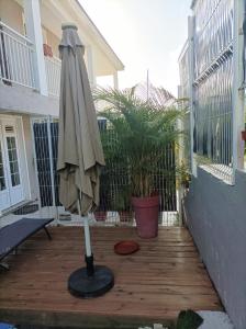 an umbrella sitting on a patio next to a house at CHEZ COCO appartement BALISIER in Rivière-Salée