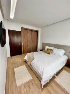 a bedroom with a white bed with a teddy bear on it at SIAM’S House in El Harhoura