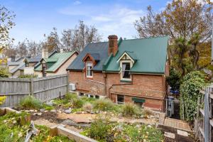 Una vieja casa de ladrillo con techo verde en Karkalla Terrace - Explore Hobart's Historic Heart, en Sandy Bay