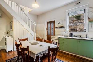 una cocina con mesa y sillas y una cocina con escalera. en Karkalla Terrace - Explore Hobart's Historic Heart, en Sandy Bay