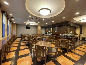 Hotel Route-Inn Fukui Ekimae في فوكوي: مطعم فيه طاولات وكراسي خشبية