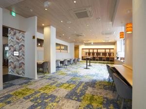 a lobby with chairs and tables in a building at Hotel New Gaea Yakuin in Fukuoka