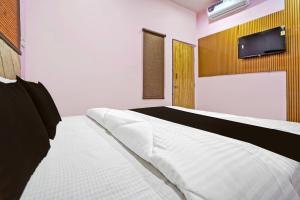 1 dormitorio con 1 cama y TV en la pared en OYO The Orchid Hotel, en Nagpur