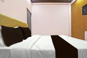 1 dormitorio con 1 cama blanca grande con almohadas negras en OYO The Orchid Hotel, en Nagpur