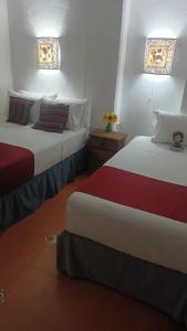 2 Betten in einem Hotelzimmer mit 2 in der Unterkunft Hostal Doña Emma in Pahuatlán del Valle