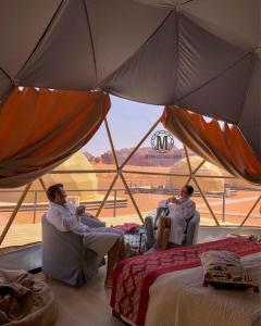 três homens sentados em cadeiras numa tenda em Moon Island Camp em Wadi Rum