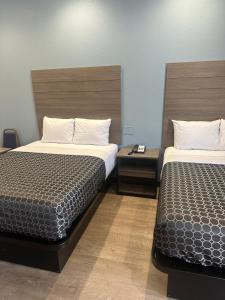 a hotel room with two beds and two tables at M&M Inn and Suites in Fort Worth