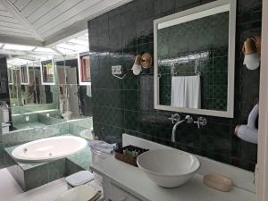 Barracuda Eco Resort Búzios في بوزيوس: حمام ذو بلاط أخضر مع حوض ومرآة