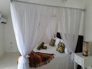 1 dormitorio con cama con dosel y almohadas en Barracuda Eco Resort Búzios, en Búzios