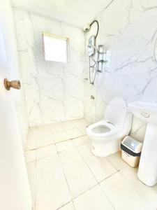 a white bathroom with a toilet and a sink at White House Villa in Dumaguete