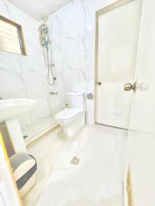 bagno bianco con servizi igienici e lavandino di White House Villa a Dumaguete