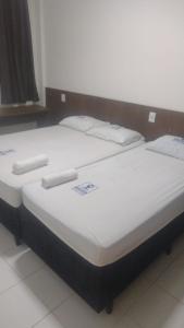 2 camas en una habitación con sábanas y almohadas blancas en HOTEL DA RODOVIARIA en Belém