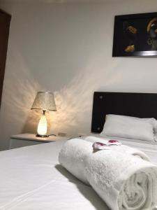 um quarto com uma cama branca e um candeeiro em San Alejo em Tuluá