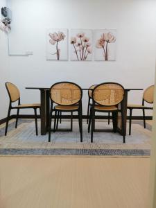 a dining room table with two chairs and paintings on the wall at casa261 HOMESTAY PD in Port Dickson