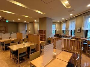 um restaurante com mesas e cadeiras de madeira e janelas em Hotel Route-Inn Morioka Ekimae em Morioka