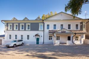 a white car parked in front of a white building at Hotel Yesenin in Murom