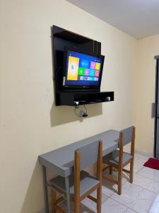 uma televisão numa parede com uma mesa e duas cadeiras em Capim dourado privativo a minutos do aeroporto em Palmas