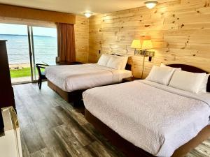 two beds in a room with a view of the ocean at Bridgeview Motel in Mackinaw City