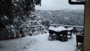 a table and chairs covered in snow on a balcony at The Oaktree House in Shimla