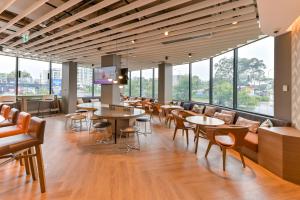 um restaurante com mesas, cadeiras e janelas em Holiday Inn Express Sydney Airport, an IHG Hotel em Sidney