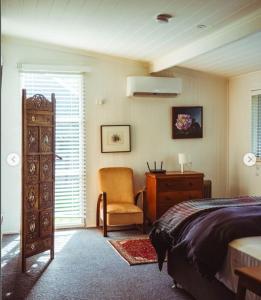 ein Schlafzimmer mit einem Bett, einem Stuhl und einer Kommode in der Unterkunft Ellerslie Cottage in Metcalfe