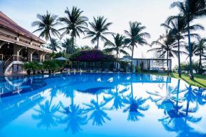 a pool at the resort with palm trees in the background at Sunny Beach Resort & Spa in Mui Ne
