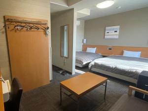 a hotel room with two beds and a table at Hotel Route-Inn Kakegawa Inter in Kakegawa