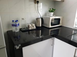 a kitchen counter with a microwave and bottles of water at 1Bedroom Urban Oasis Retreat in Melaka +2 photos