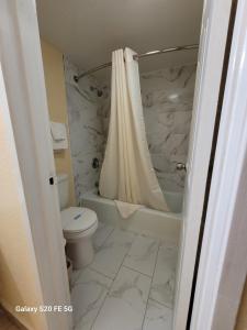 a bathroom with a toilet and a shower with a shower curtain at La Vista Motel in Brownsville
