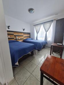 アリカにあるAlto Chinchorro Hostelのベッドルーム1室(ベッド2台、テーブル、ベンチ付)