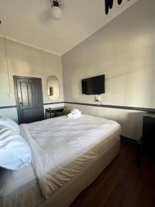 a bedroom with a white bed and a flat screen tv at The Federal Hotel in Kalgoorlie