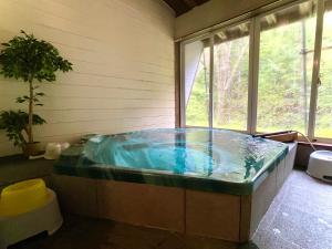 a jacuzzi tub in a room with a window at 乗鞍高原の宿テンガロンハットB&BTengallonhat in Matsumoto