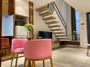 a living room with pink chairs and a staircase at Zhongshan Perth Hotel Apartment - Shiqi Wanxianghui Branch in Zhongshan