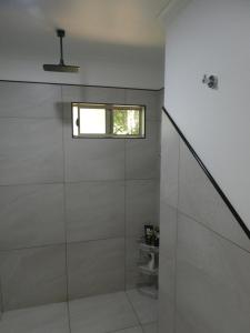 a bathroom with a glass shower with a window at Vista Hinchinbrook in Cardwell