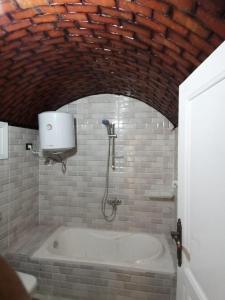 a bath tub in a bathroom with a brick wall at Aswan in Naj‘ al Maḩaţţah