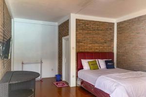 1 dormitorio con cama y pared de ladrillo en Urbanview Hotel Villa Q Gisting en Banjarnegeri