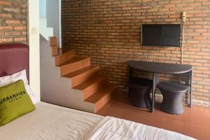 a bedroom with a staircase and a table and a tv at Urbanview Hotel Villa Q Gisting by RedDoorz in Banjarnegeri
