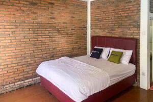 a bed with two pillows on it next to a brick wall at Urbanview Hotel Villa Q Gisting by RedDoorz in Banjarnegeri