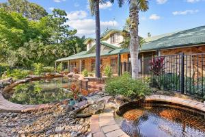 a home with a pond in front of a house at Spacious 4-Bed Hinterland Luxury Escape with Pool in Gold Coast