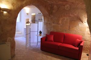 マテーラにあるCasa Vacanza Il Fontanino nel cuore dei Sassiの石壁の部屋の赤いソファ