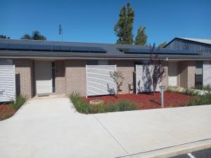 un edificio in mattoni con porte bianche e un vialetto di French Corner Apartments a Dubbo