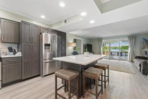 a kitchen with a refrigerator and a table with stools at Water Front Condo with Boat Slip: The Dock House in Elizabeth City
