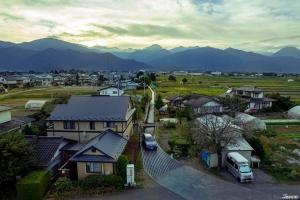 uma aldeia com casas e uma carrinha estacionada em frente às montanhas em Shino's Farm Inn em Azumino