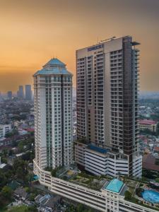 ジャカルタにあるSomerset Sudirman Jakartaの日没時の都市の高層ビル2棟