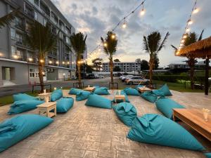 un patio con almohadas y mesas azules y un edificio en Panphuree Residence - SHA Extra Plus, en Nai Yang Beach