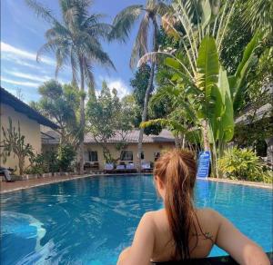 a woman sitting in front of a swimming pool at Xin Chao Hotel in Mui Ne