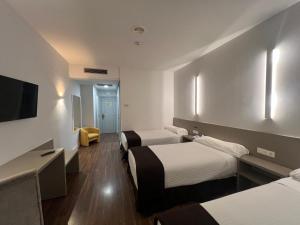 Habitación de hotel con 2 camas y TV de pantalla plana. en Hotel Alfonso IX en Sarria