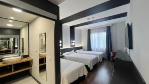 a hotel room with two beds and a mirror at Hotel Alfonso IX in Sarria