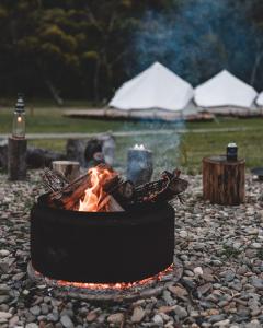 a fire pit on a rocky ground with a tent at Tathra Beach Eco Camp in Tathra