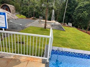 a white fence next to a swimming pool at Wild Brooke Hut in Vythiri